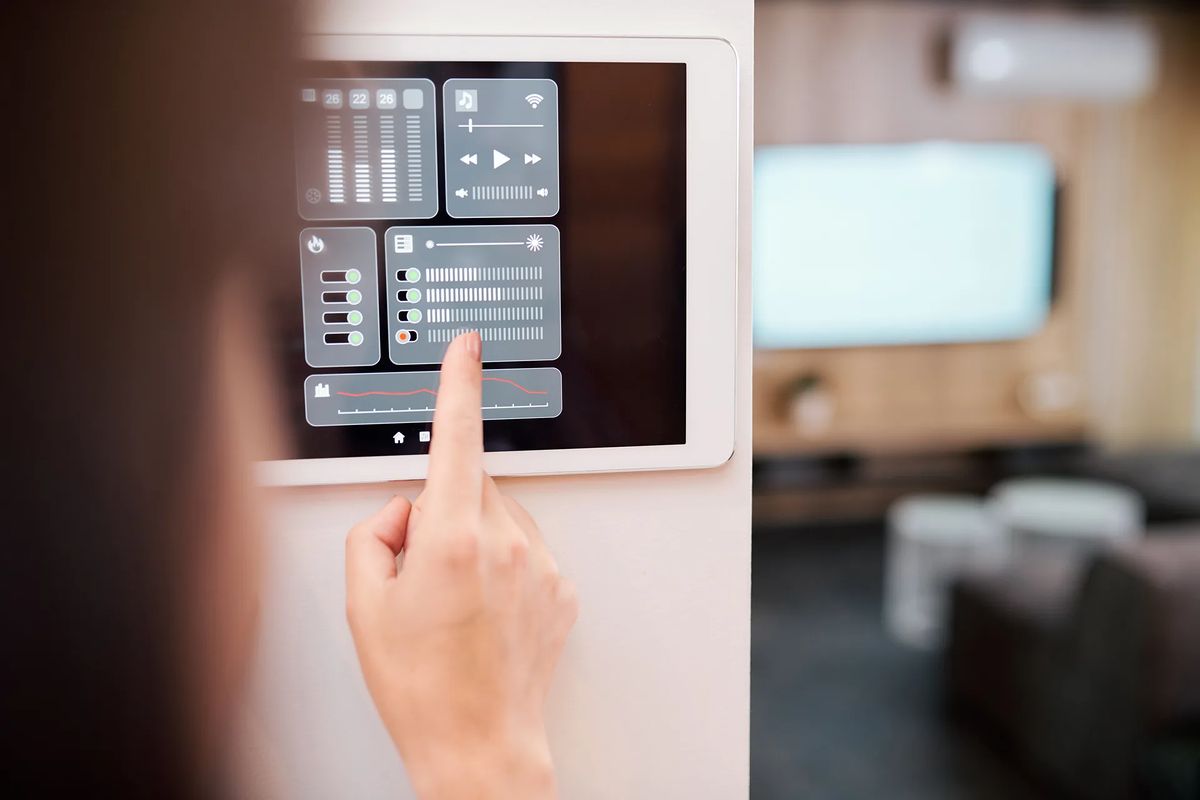 Dito che sfiora un pannello touch screen a muro per il controllo di clima, luci e diffusione musicale
