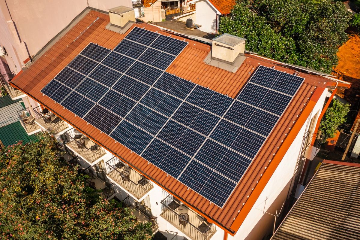 Vista aerea di un impianto fotovoltaico sul tetto in coppi di un edificio residenziale con balconi