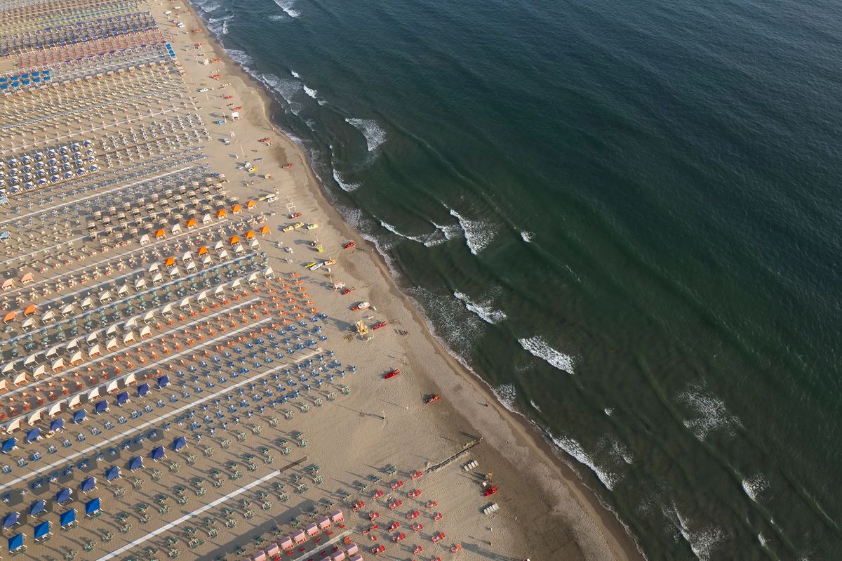 Vista aerea di uno stabilimento balneare in Versilia con file di ombrelloni colorati sulla spiaggia