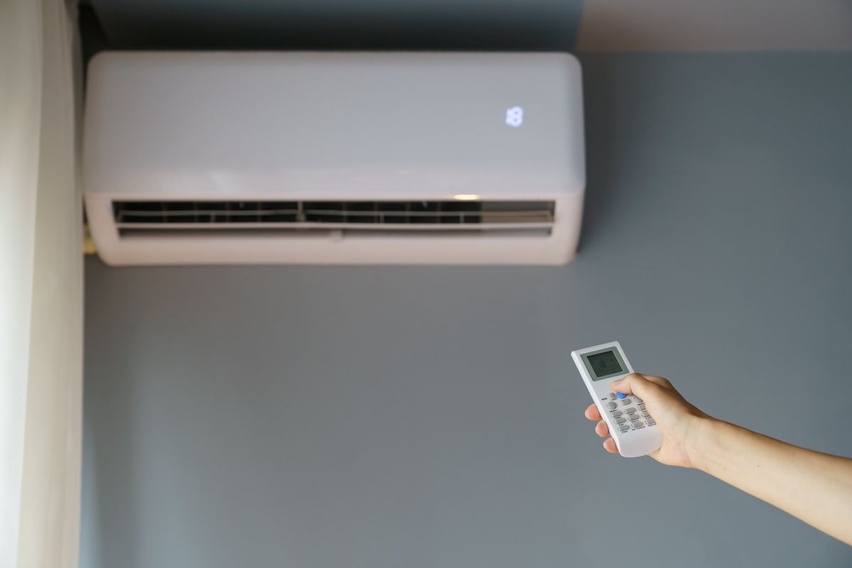 Mano che imposta la temperatura del climatizzatore a parete con il telecomando