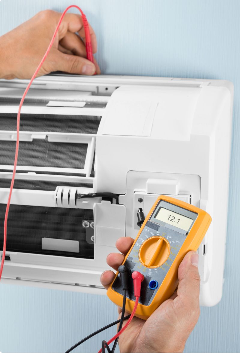 Tecnico che misura con il multimetro i collegamenti di un climatizzatore split
